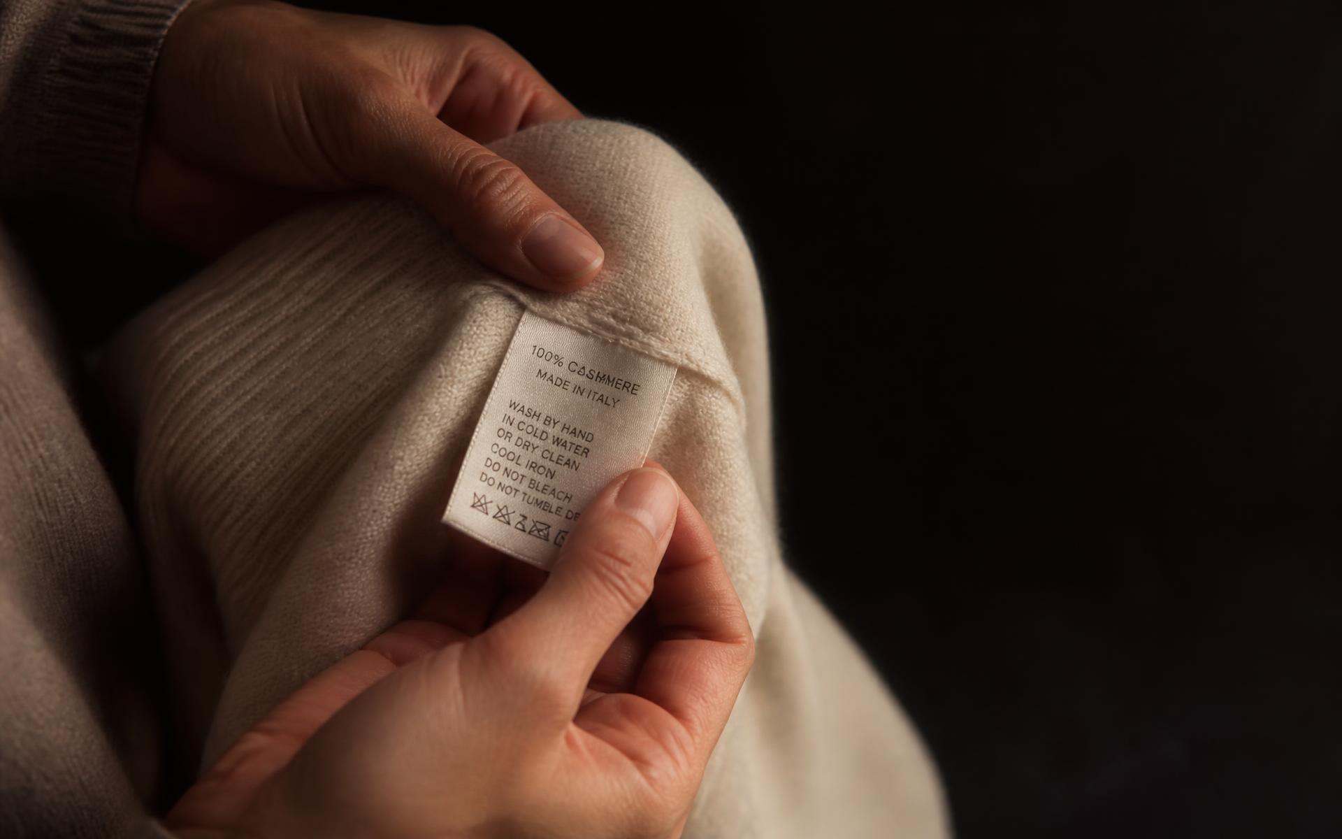 Hands holding the care label inside a cashmere sweater